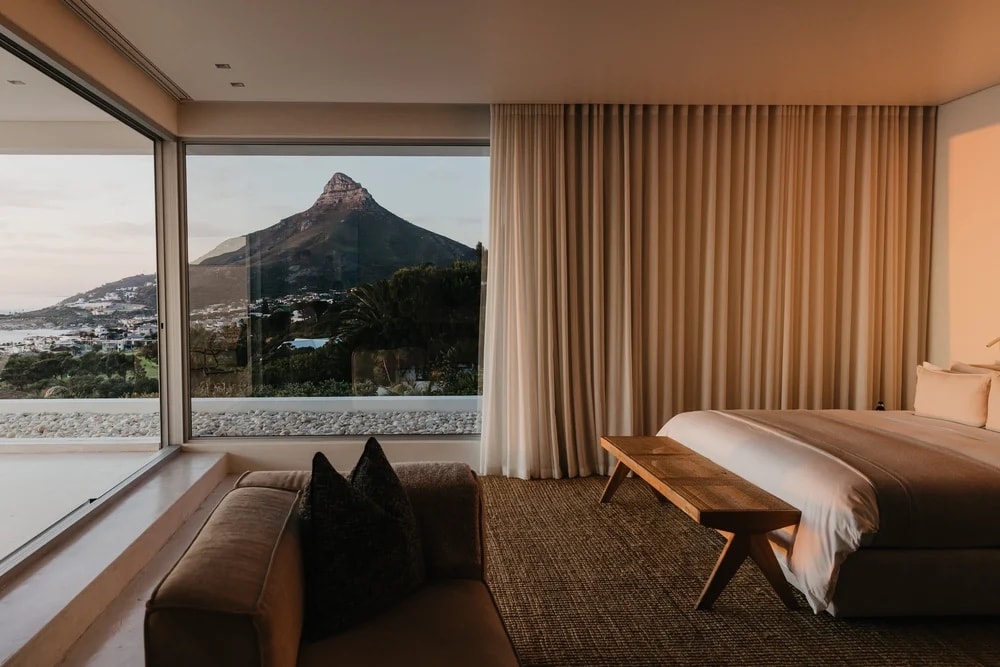 A bedroom at dusk, the window open the full width of the wall and Lion's Head in it